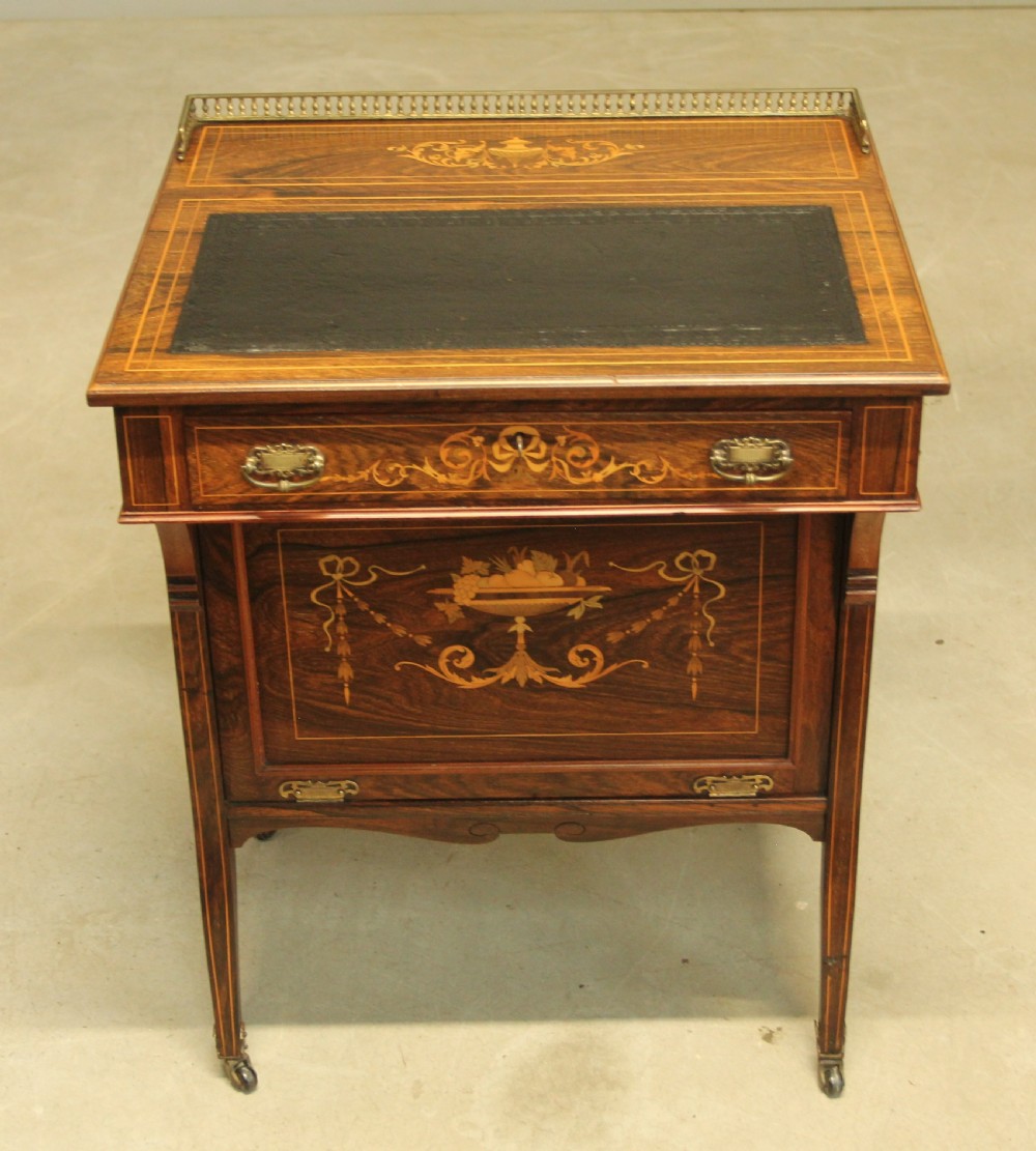 A Victorian rosewood Davenport desk featuring fine floral marquetry inlay, a black leather writing surface, a brass gallery rail, and slender tapered legs on brass castors. View II