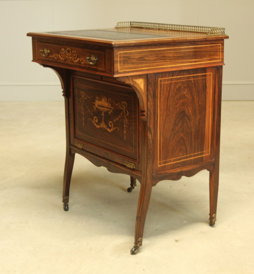 A Victorian rosewood Davenport desk featuring fine floral marquetry inlay, a black leather writing surface, a brass gallery rail, and slender tapered legs on brass castors. View VII