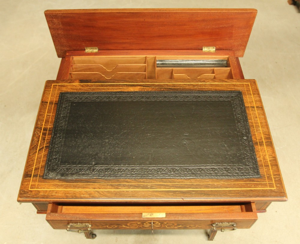 A Victorian rosewood Davenport desk featuring fine floral marquetry inlay, a black leather writing surface, a brass gallery rail, and slender tapered legs on brass castors. View IX