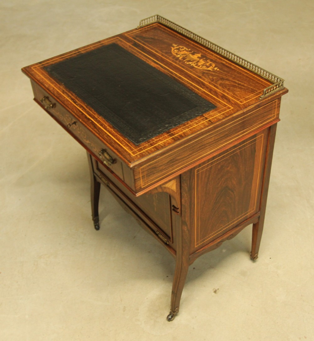 A Victorian rosewood Davenport desk featuring fine floral marquetry inlay, a black leather writing surface, a brass gallery rail, and slender tapered legs on brass castors. View X