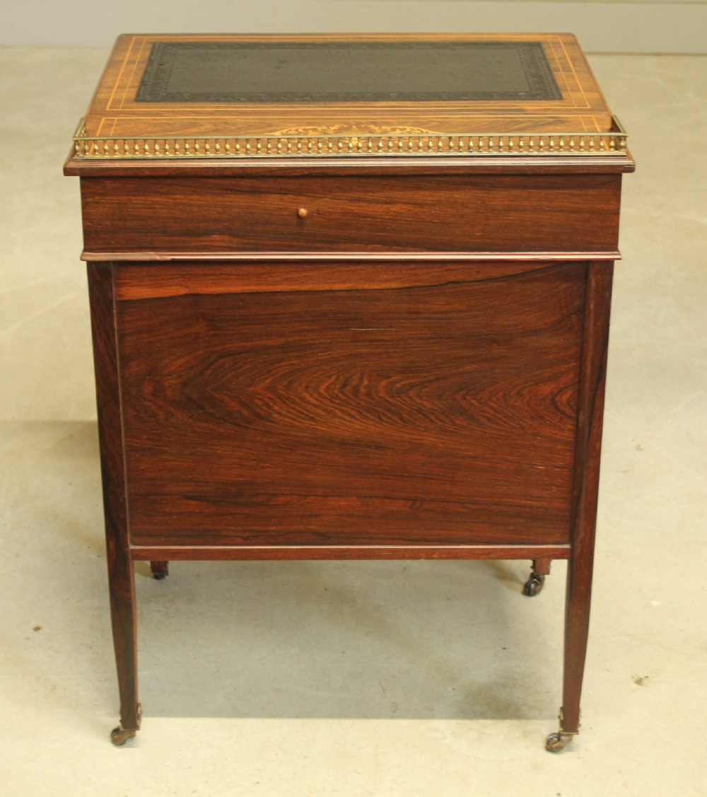 A Victorian rosewood Davenport desk featuring fine floral marquetry inlay, a black leather writing surface, a brass gallery rail, and slender tapered legs on brass castors. View XI