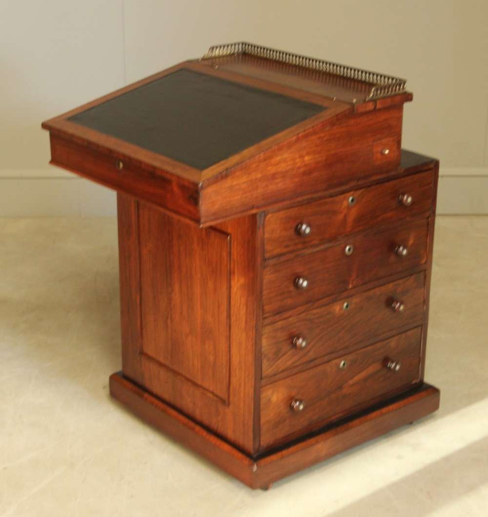 An early 19th-century rosewood Davenport desk featuring a slanted leather-inset writing surface, brass top gallery rail, and side drawers. View V