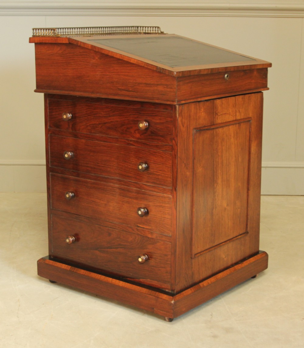 An early 19th-century rosewood Davenport desk featuring a slanted leather-inset writing surface, brass top gallery rail, and side drawers. View VII