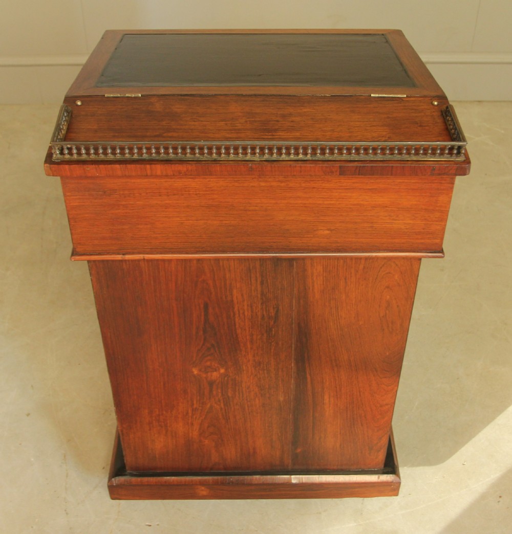 An early 19th-century rosewood Davenport desk featuring a slanted leather-inset writing surface, brass top gallery rail, and side drawers. View IX