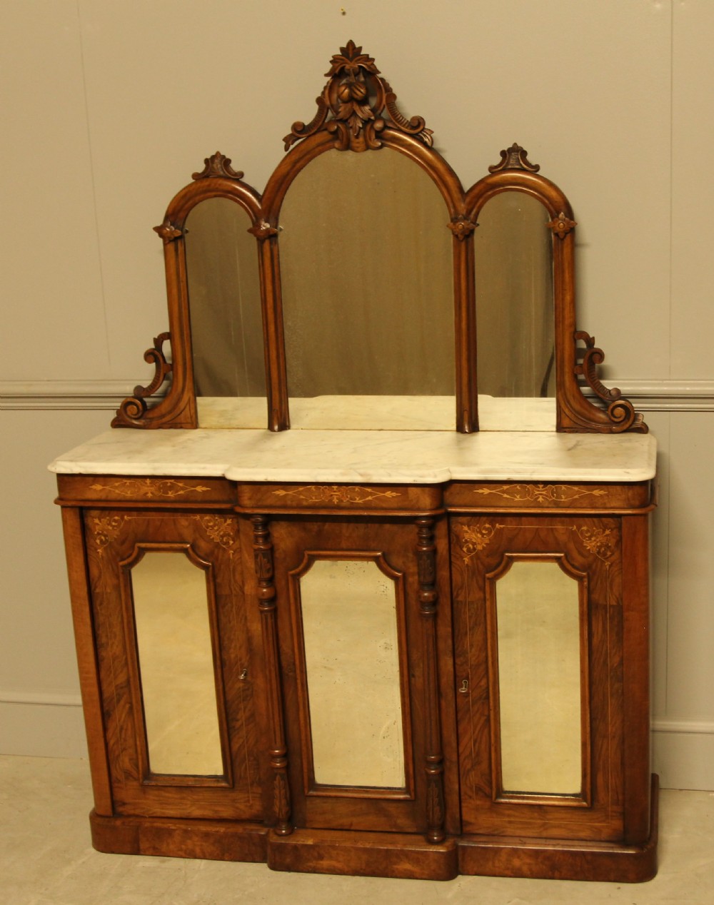 A Victorian burr walnut credenza with a white marble top, arched tri-fold mirror back, and three mirrored cabinet doors below. View III