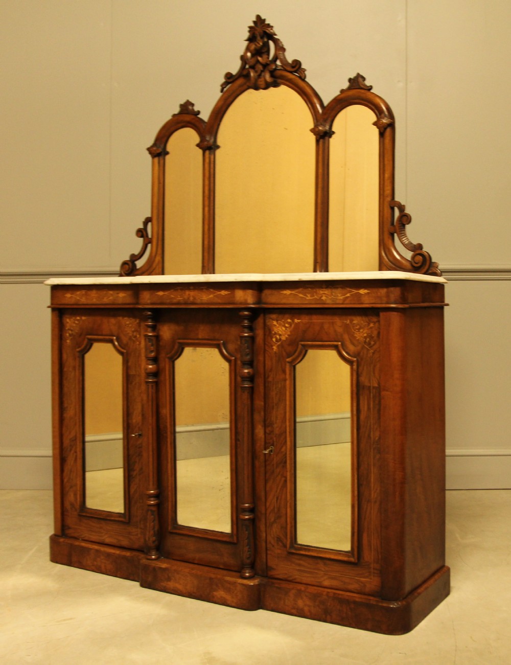 A Victorian burr walnut credenza with a white marble top, arched tri-fold mirror back, and three mirrored cabinet doors below. View VII