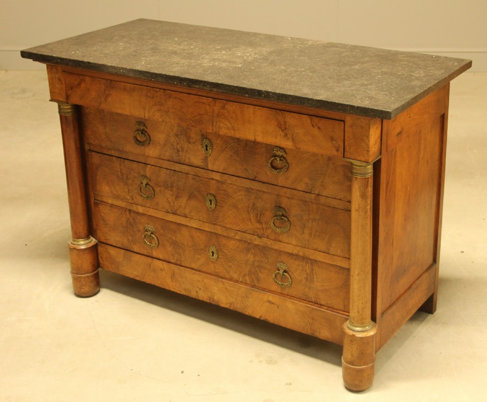 A 19th-century French burr walnut chest of drawers featuring three main drawers with brass ring handles, architectural side columns, and a dark marble top. View VII
