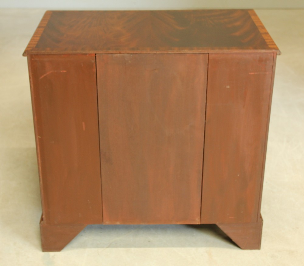 An early 20th-century mahogany kneehole desk featuring seven drawers with brass handles, a central recessed cupboard, and bracket feet. View XI