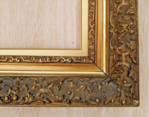 fig 1. An ornate rectangular Victorian gilt picture frame featuring detailed foliage and scroll relief moulding around a stepped inner border.