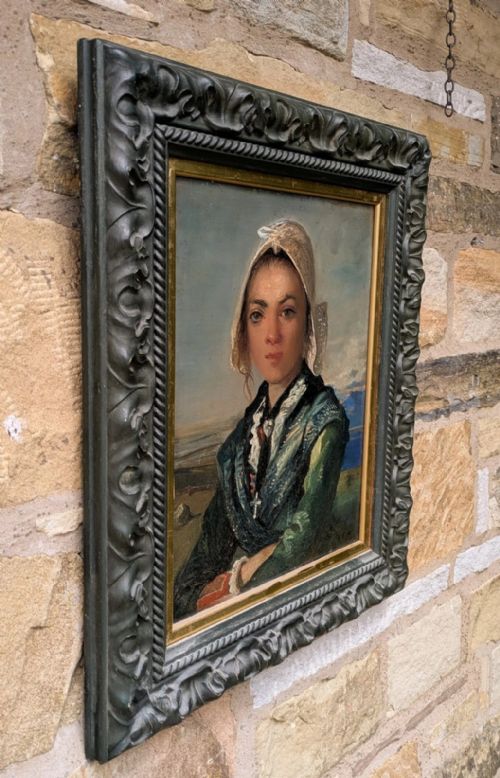 fig 1. An antique oil painting on board depicting a young girl in traditional dress and bonnet, framed in a dark carved frame with a gold inner border.