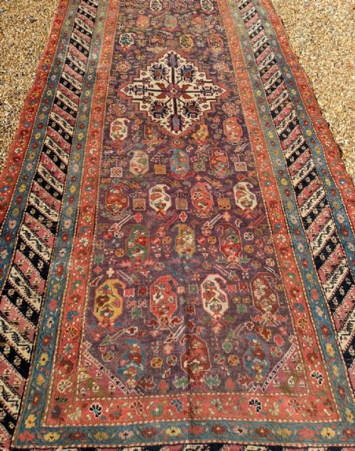 fig 1. An antique hand-knotted Karabagh wool carpet runner featuring a central cream medallion, scattered boteh motifs, and a barber-pole diagonal border on a dark aubergine field.