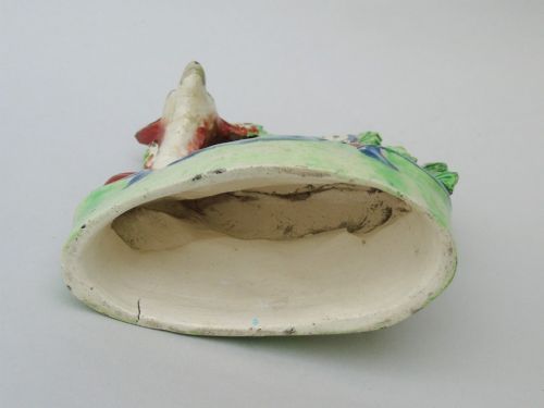 fig 1. An early nineteenth-century Staffordshire pearlware figure depicting a recumbent brown and white doe positioned in front of a green bocage flower canopy.