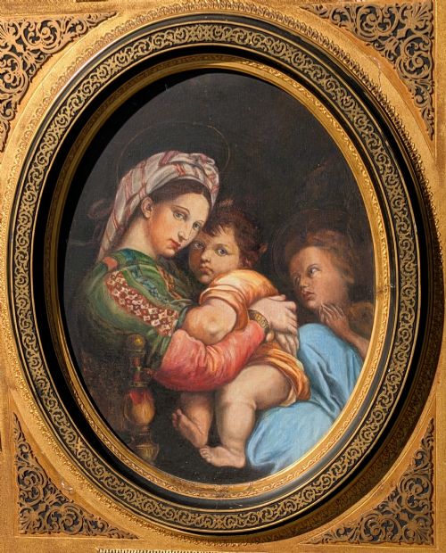 fig 1. An oval oil painting depicting Mary holding the infant Christ alongside Saint John, set within an ornate gilded frame with corner fretwork.