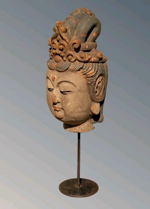 A carved wooden head of a Buddhist deity featuring an ornate tall crown, serene facial features, and residual surface pigments. View VII