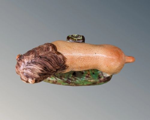 An early nineteenth-century Staffordshire pearlware lion figure featuring an ochre-tinted body with one paw resting on a yellow sphere, set upon a moulded green and brown glaze base. View VIII