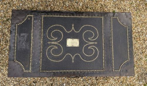 fig 1. A dark brown leather rectangular coffer decorated with brass stud patterns, scrolling motifs, and a central metal latch.