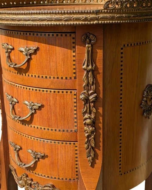 fig 2. A circular French-style bedside cabinet crafted from inlaid kingwood, featuring three drawers, brass mounts, a top gallery rim, and cabriole legs.