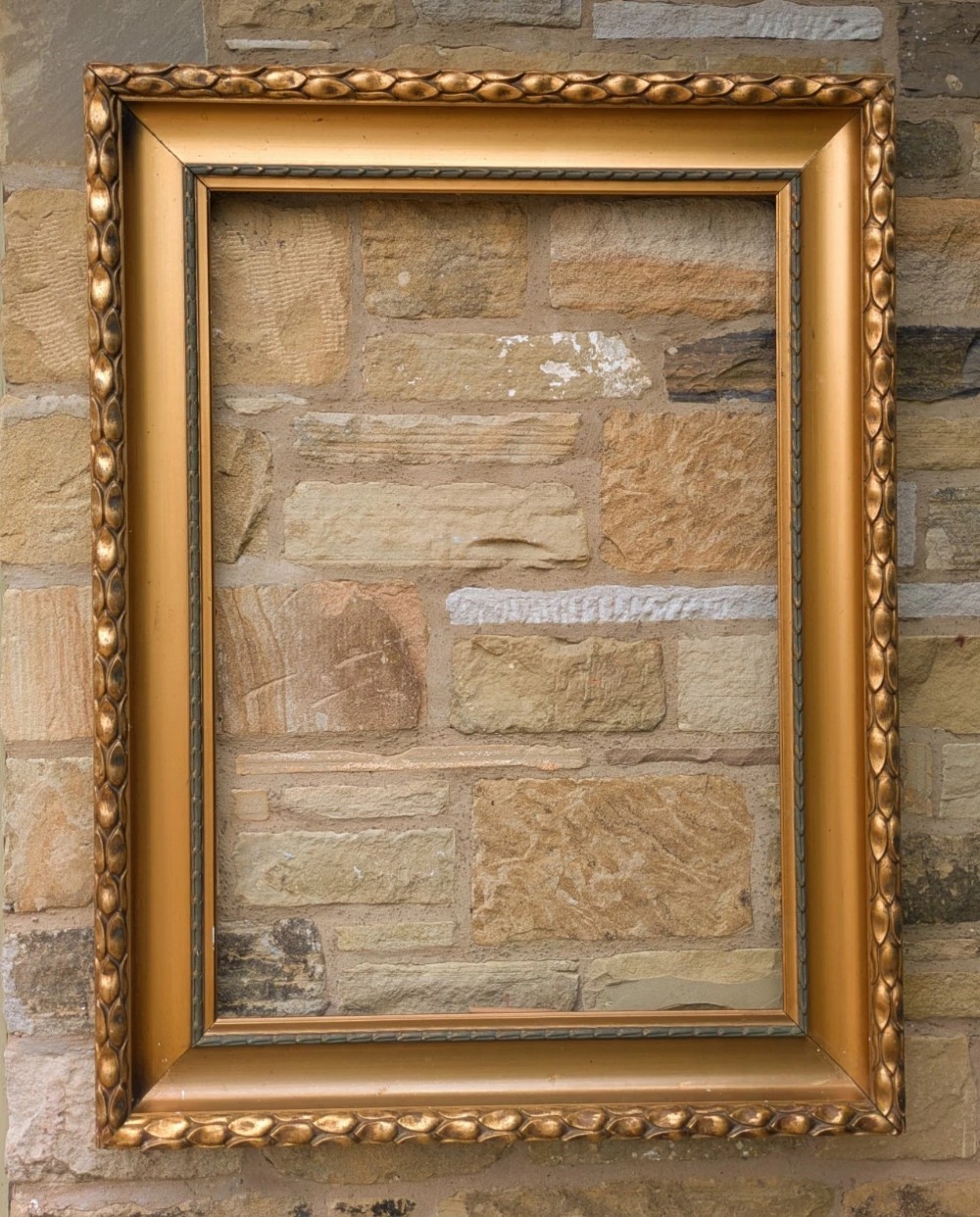 A rectangular Empire style giltwood picture frame featuring carved outer egg-and-dart moulding and a smooth inner cove profile.