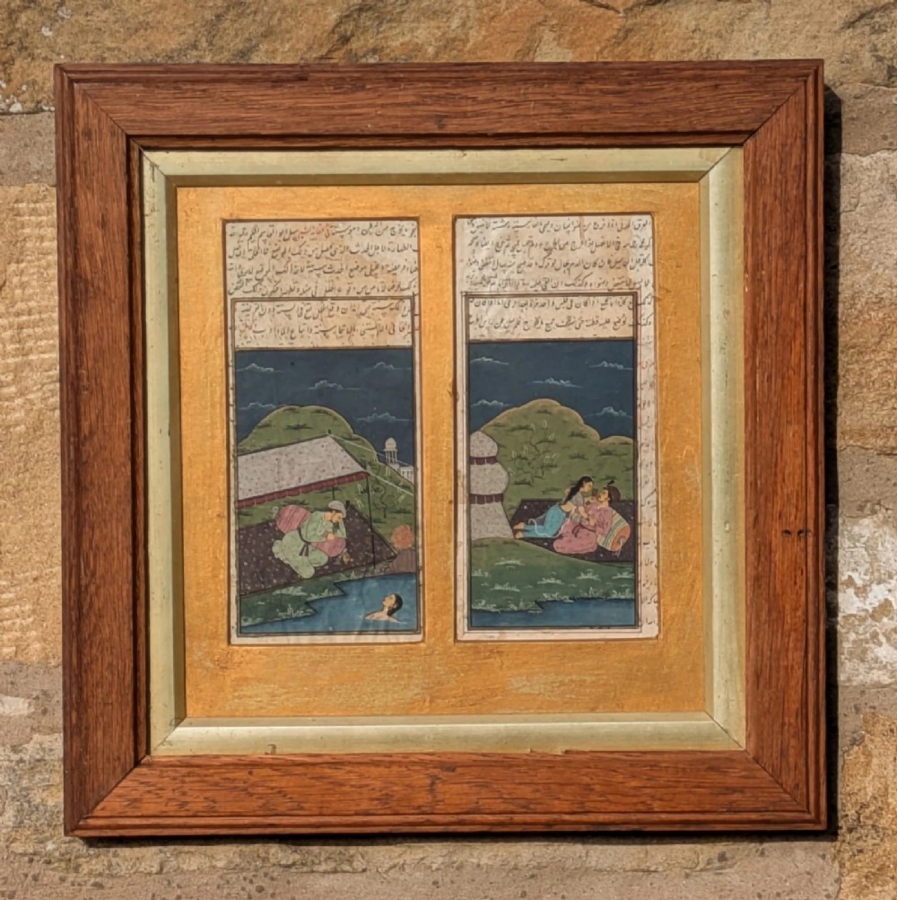 A double-panelled Mughal style gouache painting on paper featuring lovers in a landscape with calligraphic text, framed in wood with a gold mount.