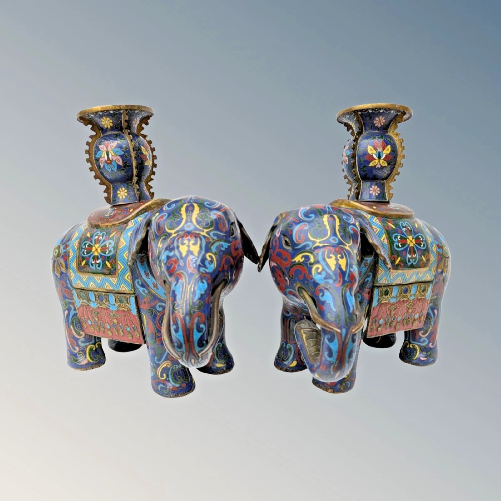 A pair of Chinese cloisonne enamel elephant statues patterned with colourful geometric scrolls, each supporting a decorative vase upon its saddle.