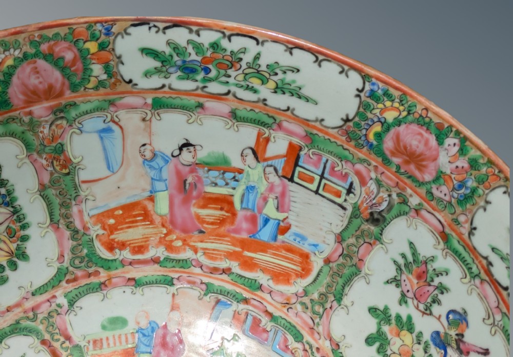 A top-down view of a circular 19th-century Chinese porcelain bowl featuring hand-painted Famille Rose enamels with alternating panels of figures and floral motifs. View IV