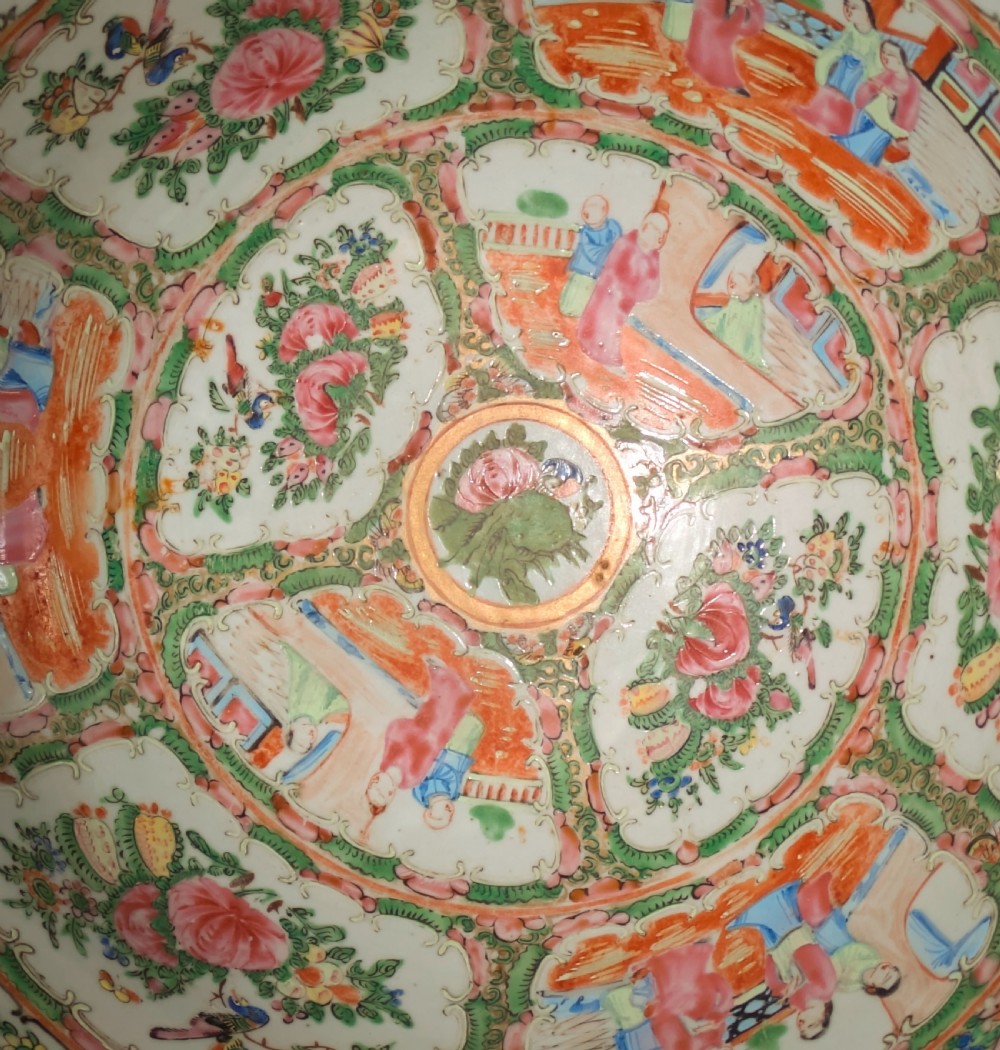 A top-down view of a circular 19th-century Chinese porcelain bowl featuring hand-painted Famille Rose enamels with alternating panels of figures and floral motifs. View V