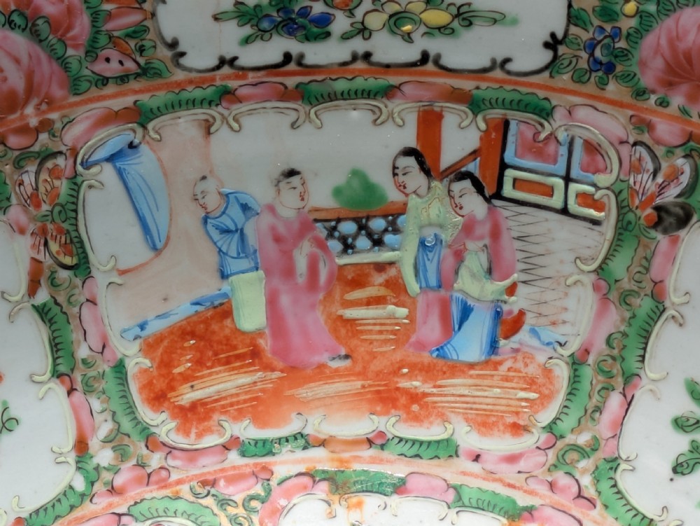 A top-down view of a circular 19th-century Chinese porcelain bowl featuring hand-painted Famille Rose enamels with alternating panels of figures and floral motifs. View VII