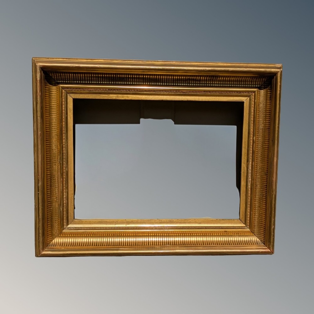 A deep rectangular Victorian gilt picture frame featuring reeded mouldings and a gold leaf finish.
