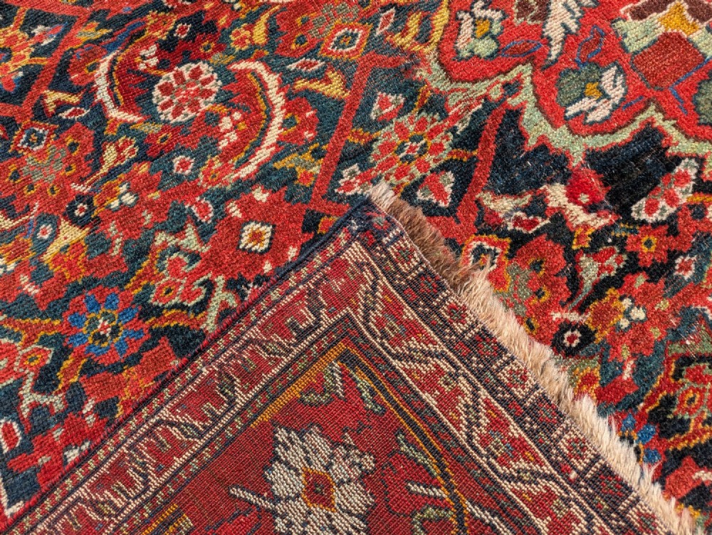 A rectangular hand-knotted Persian Khamseh carpet featuring three central floral medallions on a dense red patterned field with decorative borders. View VII