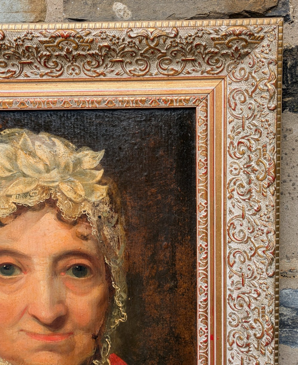 An antique 19th-century oil portrait depicting an elderly woman in a lace cap and red patterned shawl, framed in a carved gilt wood frame. View VI