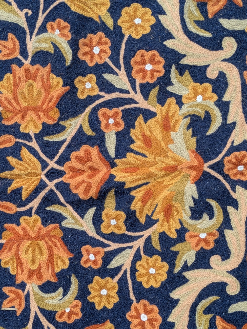 A rectangular Kashmir chain stitch rug featuring dense floral embroidery, a central medallion, and borders in red, navy blue, and gold tones. View III