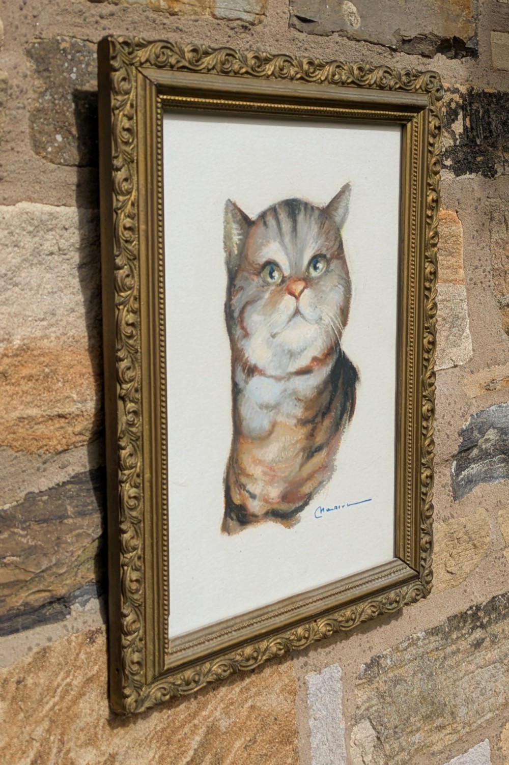 A framed pastel portrait depicting a grey and brown tabby cat set inside an ornate gold-coloured molded frame. View II