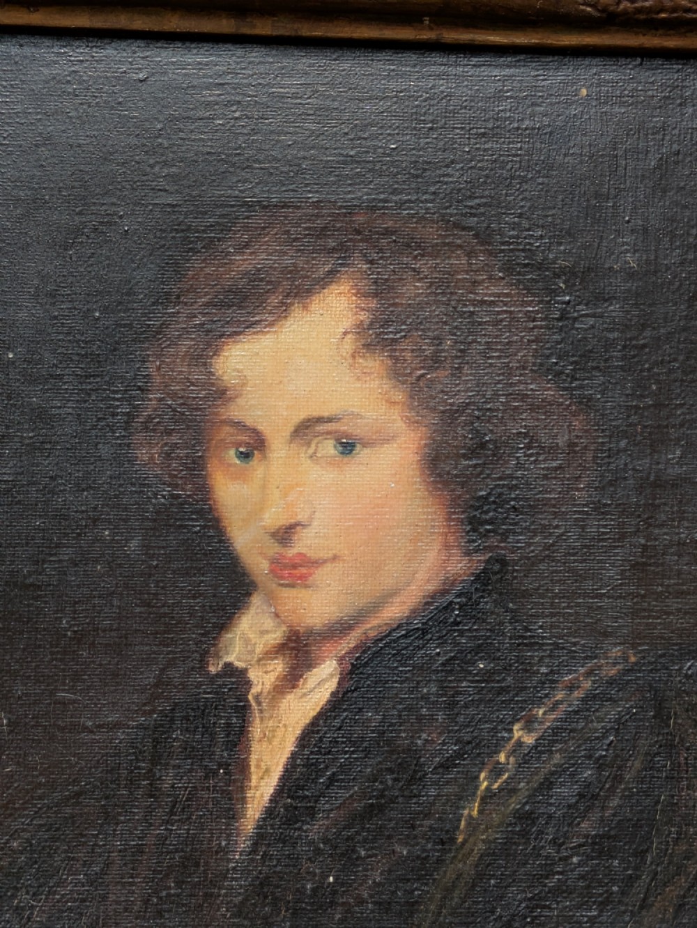 An antique oil painting depicting a young gentleman with dark wavy hair and an open collar set within a decorated metallic gilt frame. View IV