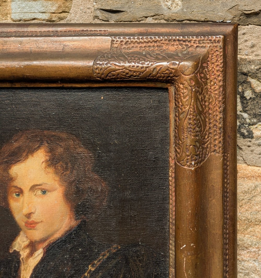 An antique oil painting depicting a young gentleman with dark wavy hair and an open collar set within a decorated metallic gilt frame. View V