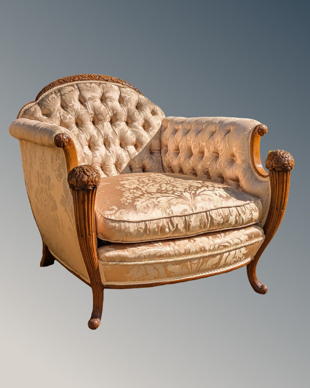 An antique French armchair featuring a carved walnut frame, button-tufted back, and champagne silk damask upholstery.