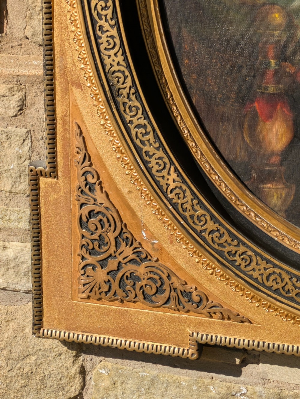 An oval oil painting depicting Mary holding the infant Christ alongside Saint John, set within an ornate gilded frame with corner fretwork. View IV