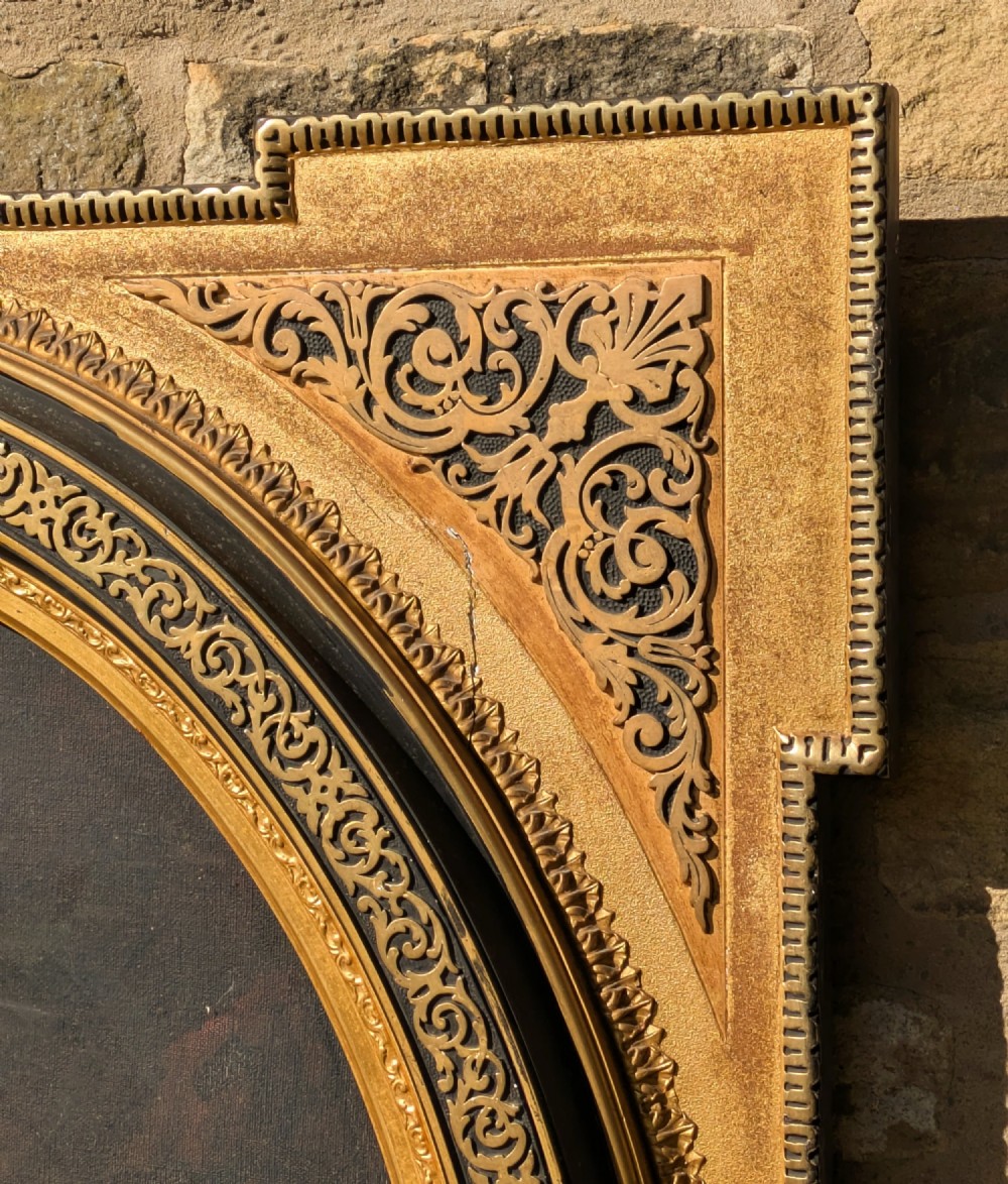 An oval oil painting depicting Mary holding the infant Christ alongside Saint John, set within an ornate gilded frame with corner fretwork. View V