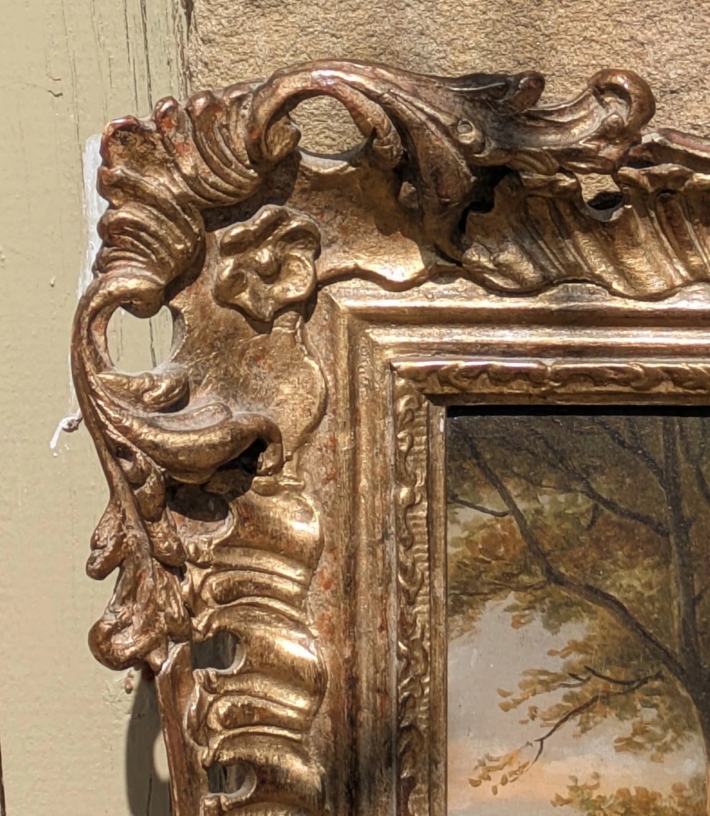 A 19th-century oil painting depicting a barefoot young woman standing outdoors in front of a cottage wall beside potted flowers, set within a deeply carved gilt frame. View VI