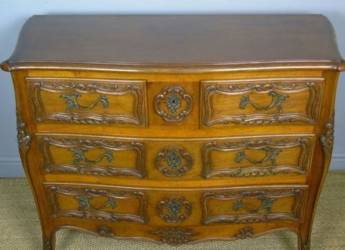 A French walnut chest of drawers featuring three carved drawer fronts, ornate brass handles, a decorative carved apron, and short cabriole legs. View II