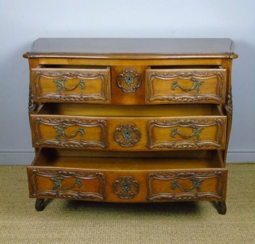 A French walnut chest of drawers featuring three carved drawer fronts, ornate brass handles, a decorative carved apron, and short cabriole legs. View III