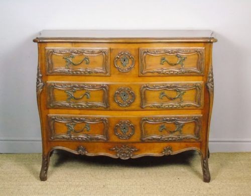 A French walnut chest of drawers featuring three carved drawer fronts, ornate brass handles, a decorative carved apron, and short cabriole legs. View VIII