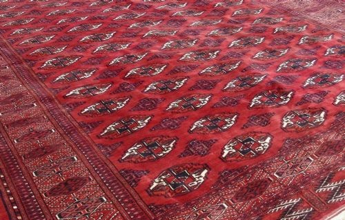 A rectangular hand-knotted wool Tekke carpet featuring repeating octagonal gul motifs across a rich red field surrounded by geometric borders. View II