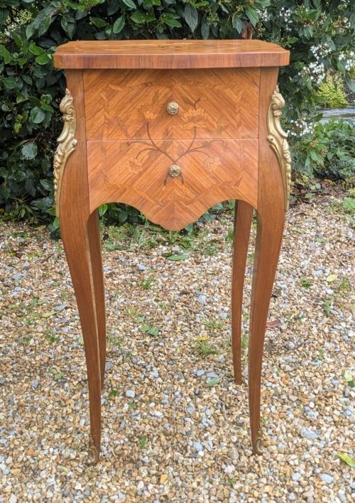 A pair of French Kingwood bedside cabinets featuring floral marquetry inlays, curved cabriole legs, and polished brass mounts. View VII