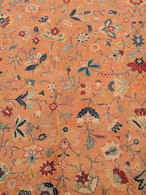 An antique hand-knotted Tabriz carpet featuring a terracotta central field decorated with intricate floral motifs and framed by layered ivory and navy decorative borders. View IV