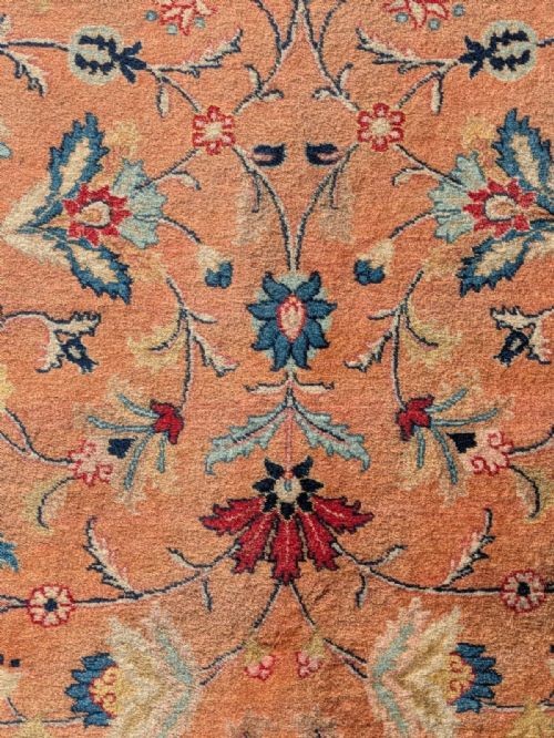 An antique hand-knotted Tabriz carpet featuring a terracotta central field decorated with intricate floral motifs and framed by layered ivory and navy decorative borders. View V
