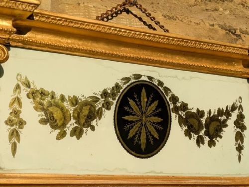 A tall rectangular Regency giltwood pier mirror featuring fluted side columns, an architectural pediment, and an upper verre eglomise panel with gilded swags. View IX