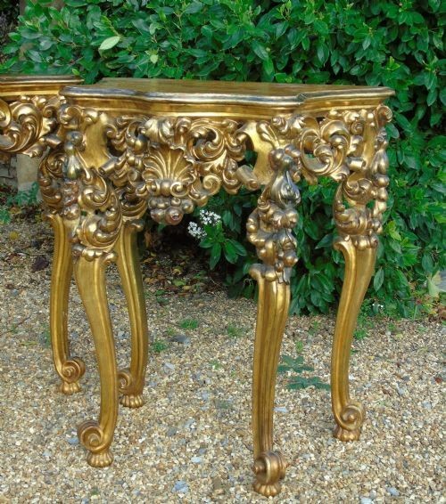 A pair of ornate Spanish giltwood console tables featuring deeply carved shell aprons and cabriole legs resting on scroll feet. View II