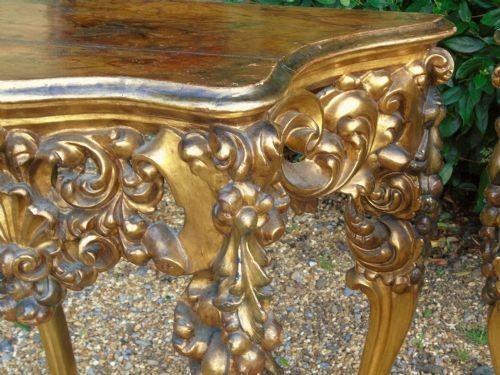 A pair of ornate Spanish giltwood console tables featuring deeply carved shell aprons and cabriole legs resting on scroll feet. View III