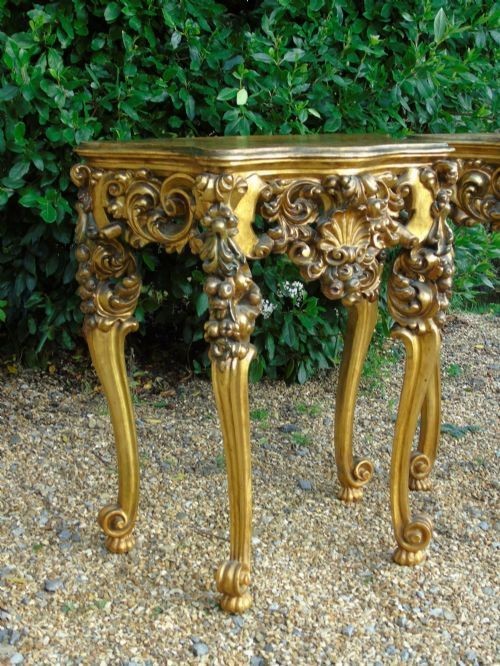 A pair of ornate Spanish giltwood console tables featuring deeply carved shell aprons and cabriole legs resting on scroll feet. View V
