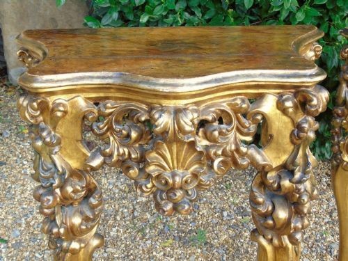 A pair of ornate Spanish giltwood console tables featuring deeply carved shell aprons and cabriole legs resting on scroll feet. View VII
